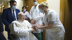Eine Krankenschwester schüttelt dem katholischen Kirchenoberhaupt die Hand. (Bild: Vatican Media)