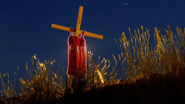 Ein Kleidchen hängt bei einer Autobahn in Kanada auf einem Holzkreuz. Es soll an die Kinder erinnern, die in den vergangenen Wochen in Hunderten Massengräbern gefunden wurden. (Bild: APA/AFP/Cole Burston)