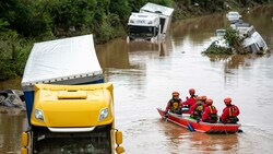 Helfer der Wasserwacht untersuchen von einem Boot aus Lastwagen, die auf der überfluteten Bundesstraße 265 stehen. (Bild: APA/dpa/Marius Becker)