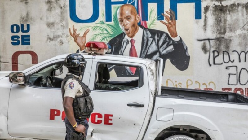 Ein Polizist steht vor einem Wandbild des ermordeten Präsidenten Jovenel Moise. Das Attentat stürzte Haiti in eine tiefe Krise. (Bild: APA/AFP/Valerie Baeriswyl)