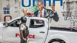 Ein Polizist steht vor einem Wandbild des ermordeten Präsidenten Jovenel Moise. Das Attentat stürzte Haiti in eine tiefe Krise. (Bild: APA/AFP/Valerie Baeriswyl)