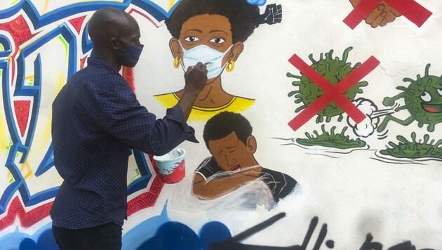 Der kongolesische Künstler Chris Shongo bemalt wie Außenwand der Kunstakademie in Kinshasa. (Bild: AFP)