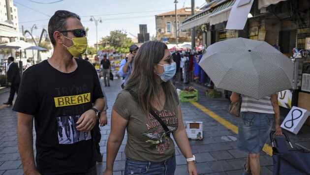 Dieses Paar in Jerusalem spaziert mit OP-Masken ausgerüstet durch Jerusalem. (Bild: AFP)