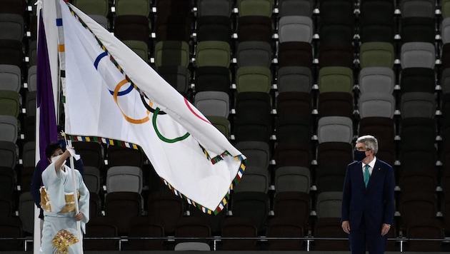 Tokyo-Bürgermeisterin Yuriko Koike (L) mit der Flagge, vorne spricht IOC-Präsident Thomas Bach. (Bild: AFP)
