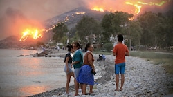 Touristen beobachten besorgt die Brände nahe der Küstenstadt Oren. (Bild: APA/AFP/STR)