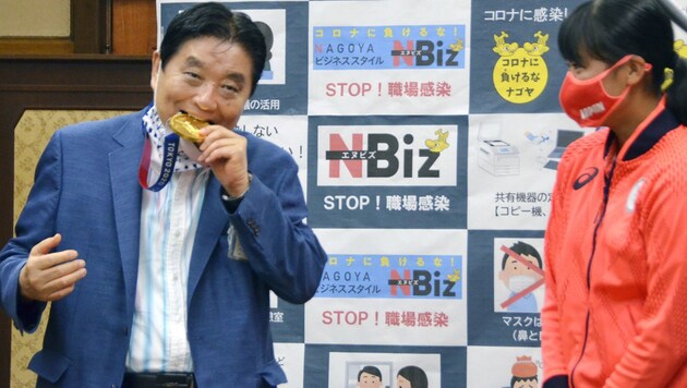 Bürgermeister Takashi Kawamura, links, testet die Medaille. Rechts daneben das verlegene Lächeln von Softballerin Miu Goto. (Bild: AP)
