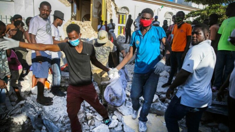Menschen bergen ein Todesopfer aus den Trümmern in Les Cayes. (Bild: AP)