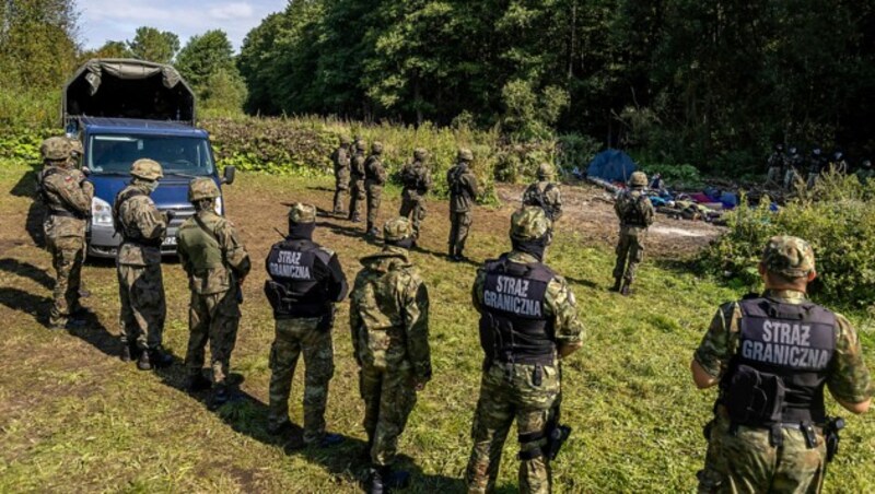 Polnische und weißrussische Grenzsoldaten umzingeln eine Gruppe afghanischer Migranten. (Bild: APA/AFP/Wojtek RADWANSKI)