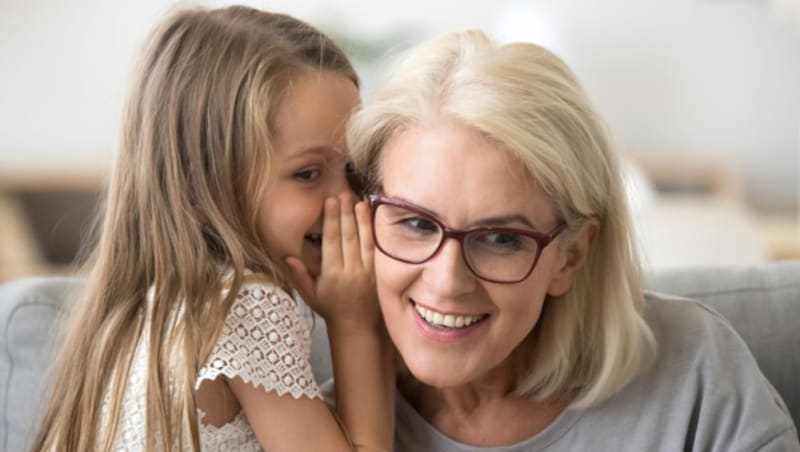 Cute little granddaughter whispering in ear telling secret to understanding smiling grandma, kid girl secretly talking to granny having fun gossiping, trust in grandmother and grandchild relations (Bild: fizkes/stock.adobe.com)