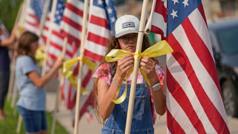 Nachbarn stellen im Ort Sandy in Utah Flaggen mit gelben Schleifen als Erinnerung an Taylor Hoover auf. Hoover war einer der 13 US-Soldaten, die bei dem Attentat am Flughafen in Kabul ums Leben kamen. (Bild: AP)