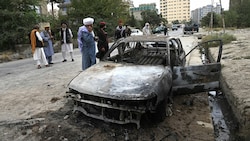 Taliban-Kämpfer inspizieren ein ausgebranntes Auto, das mit den Raketenangriff am Montag in Verbindung stehen könnte. (Bild: AFP)