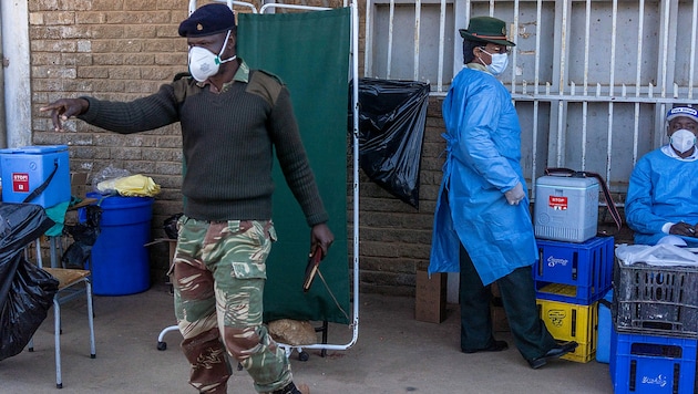 Ein Soldat kontrolliert die Warteschlange vor einer Impfstation in der Stadt Bulawayo. (Bild: APA/AFP/Zinyange Auntony)