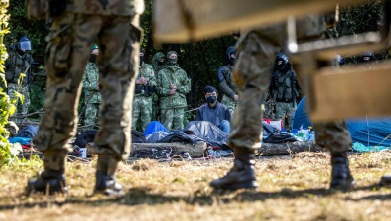 Von polnischen und weißrussischen Soldaten umringte Migranten im Grenzgebiet (Bild: APA/AFP/Wojtek RADWANSKI)