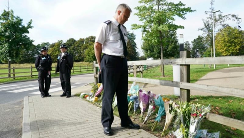 Polizisten nahe dem Tatort - zum Gedenken haben viele Menschen Blumen niedergelegt. (Bild: AP)