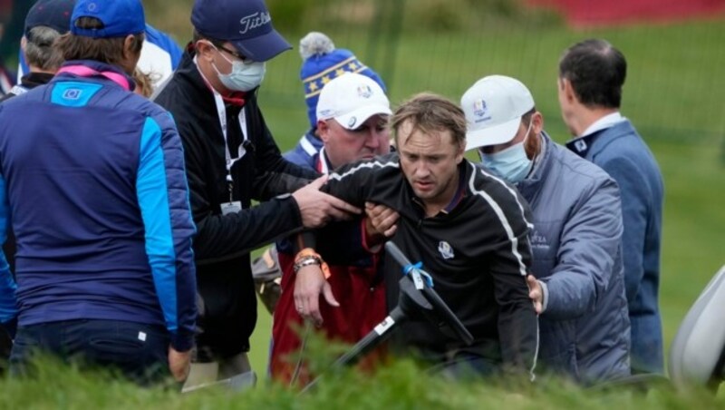 Schauspieler Tom Felton ist beim Ryder Cup Golfturnier zusammengebrochen. Helfer stützen den sichtlich angeschlagenen Star. (Bild: APA/AP Photo/Ashley Landis)