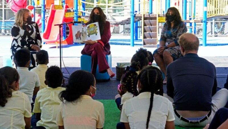 Meghan Markle liest Kindern einer New Yorker Volksschule aus ihrem Buch „The Bench“ vor. Ihr Mann Prinz Harry sitzt bei den Kindern am Boden. (Bild: Richard Drew / AP / picturedesk.com)