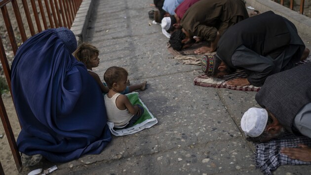 Eine Frau in Burka und zwei Kinder betteln auf den Straßen Kabuls während des Freitagsgebets. (Bild: AP)