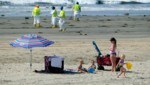 Ein skurriles Bild: Menschen sonnen sich am Strand, während Helfer unermüdlich gegen die Ölpest ankämpfen. (Bild: AP Photo/Ringo H.W. Chiu)