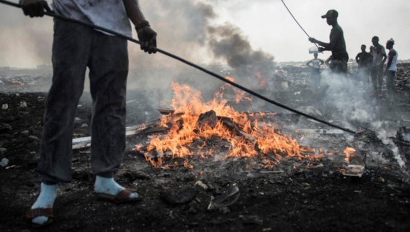 Young men burn electronic waste at Agbogbloshie dumpsite in Accra on November 29, 2017. - The dumpsite is located in Agbogbloshie slum, a former wetland in the 60's and home of refugees who fled the conflict in the north of Ghana during the 80's. (Photo by CRISTINA ALDEHUELA / AFP) (Bild: AFP)