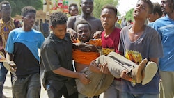 Ein bei Zusammenstößen in Khartum verletzter Mann wird in Sicherheit gebracht. (Bild: APA/AFP)