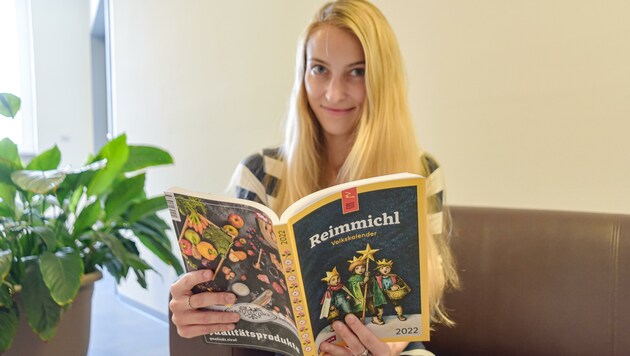 Viele Tirolerinnen und Tiroler wuchsen zu Hause mit dem „Reimmichl-Volkskalender“ auf. Auch Linda, welche angeregt in der 2022er-Ausgabe schmökert. (Bild: Hubert Berger)