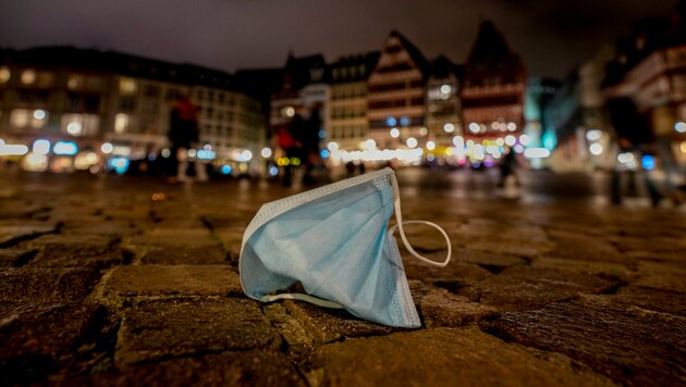 Eine liegen gebliebene Gesichtsmaske am Hauptplatz von Frankfurt. In Deutschland stieg die Inzidenz auf 191,5. (Bild: AP)