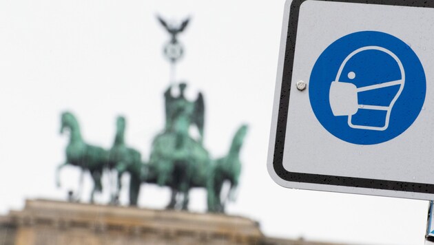 Berlin: Am Pariser Platz vor dem Brandenburger Tor weist ein Hinweisschild auf die Maskenpflicht hin (Archivbild). (Bild: APA/dpa/Christophe Gateau)