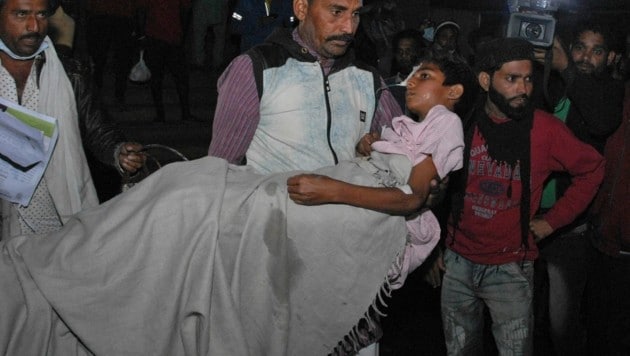 Ein Mann bringt ein Kind aus dem Kamla Nehru Kinderspital in der indischen Stadt Bhopal, wo am Montag vier Neugeborene bei einem Brand ums Leben kamen. (Bild: Associated Press)