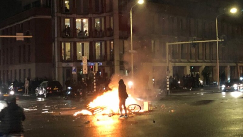 Ein Feuer auf der Straße in Den Haag während einer Demonstration. (Bild: APA/AFP/Danny KEMP)