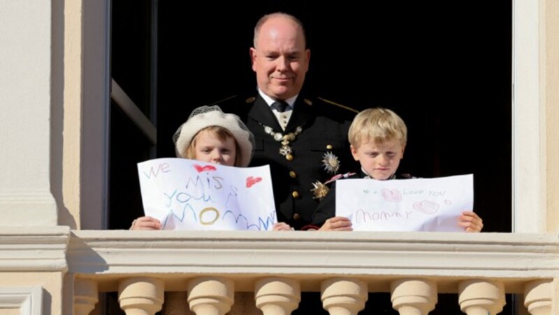 Fürst Albert mit den Zwillingen Gabriella und Jacques, die am Nationalfeiertag Grußbotschaften an ihre Mama, Fürstin Charlene, geschrieben haben (Bild: APA/Photo by Valery HACHE/AFP)