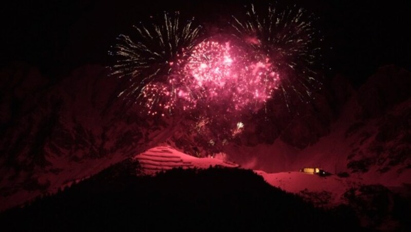 Die Nordkette in Innsbruck, durch das Licht des Feuerwerks rosarot eingefärbt. (Bild: AP Photo/Matthias Schrade)