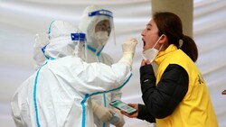 Mitarbeiter des Gesundheitsdienstes machen bei einer Frau in Xi‘an einen Covid-Abstrich. (Bild: APA/Chinatopix via AP)