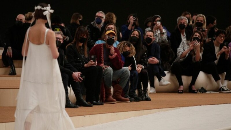 Sänger Pharell Williams, sein Sohn Rocket Ayer und seine Frau Helen blicken bei der Chanel Haute Couture Schau auf Model Caroline de Maigretim weißen Kleid. (Bild: APA/Photo by GEOFFROY VAN DER HASSELT/AFP)