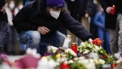 Menschen legen nach der Bluttat vor einem Gebäude der Universität Blumen und Kerzen an den Wegesrand. (Bild: APA/dpa/Uwe Anspach)