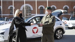 Verteidigungsministerin Klaudia Tanner übergibt Fahrzeugpapiere eines neuen Wasserstoffautos an einen Kraftfahrer der Truppe. (Bild: Carina KARLOVITS/HBF)