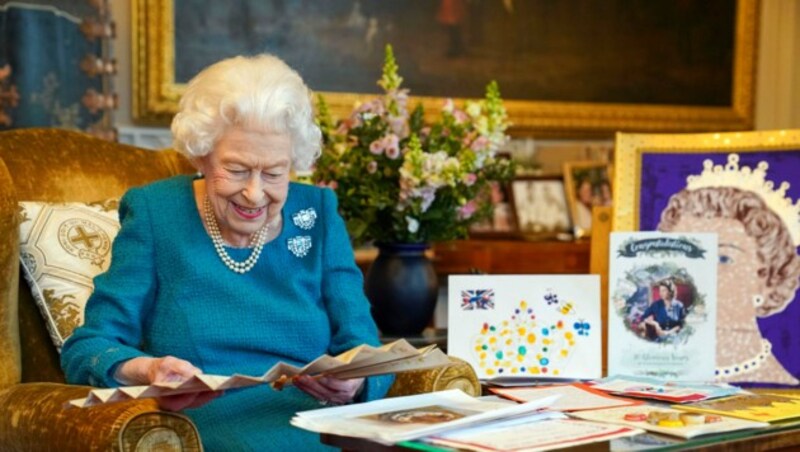 Queen Elizabeth liest sichtlich mit Vergnügen vor ihrem 70. Thronjubiläum noch einmal alte Glückwunschkarten und Andenken an zurückliegende Jubiläen. (Bild: APA/Steve Parsons/Pool via AP)