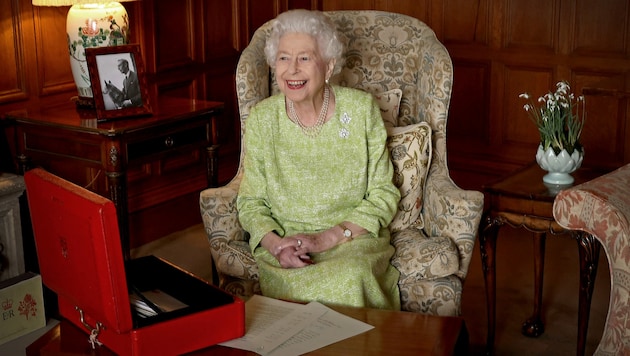 Queen Elizabeth sitzt lachend an ihrem Schreibtisch in Sandringham House in Norfolk. (Bild: APA/AFP PHOTO/BUCKINGHAM PALACE )