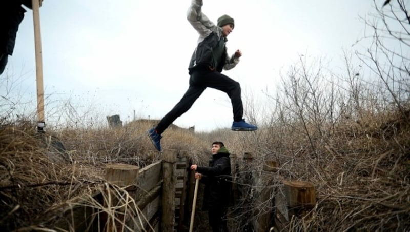 Kinder beim Spielen in einem Schützengraben in der Ostukraine (Bild: APA/AFP/Aleksey Filippov)