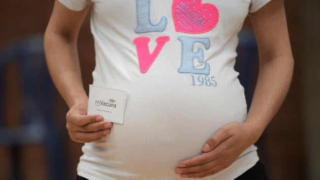 Eine schwangere Kolumbianerin zeigt ihre Impfkarte her. Eine Studie zeigt nun, dass Schwangere mit der Immunisierung auch ihre Kinder schützen. (Bild: APA/AFP/Raul ARBOLEDA)