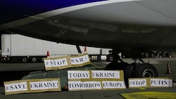 Die Crew der Antonov AN-124 hat am Flughafen Linz mit selbst gemachten Pappschildern auf die Situation in der Heimat aufmerksam gemacht. (Bild: Flughafen Linz)