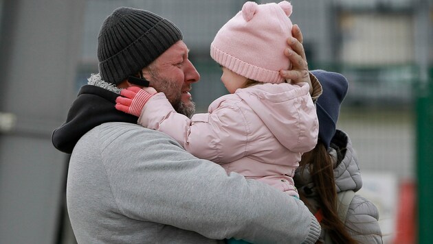 Ein Vater hält glücklich seine Tochter in den Armen. (Bild: AP Photo/Visar Kryeziu)