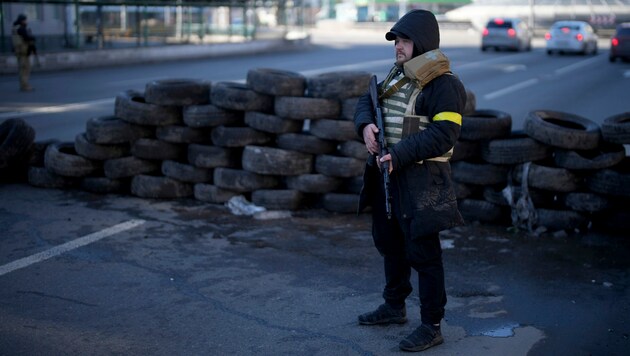 Ein bewaffneter Zivilist hält an einem Kontrollpunkt in Kiew Wache. (Bild: AP)