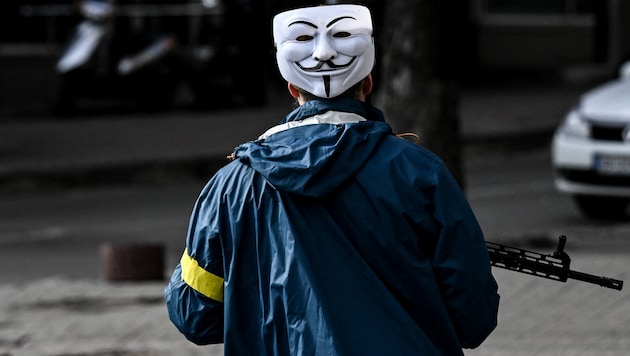 Ein Mitglied der ukrainischen Streitkräfte patrouilliert mit der als Markenzeichen von Anonymous bekannten Guy-Fawkes-Maske durch die Innenstadt von Kiew. (Bild: AFP)