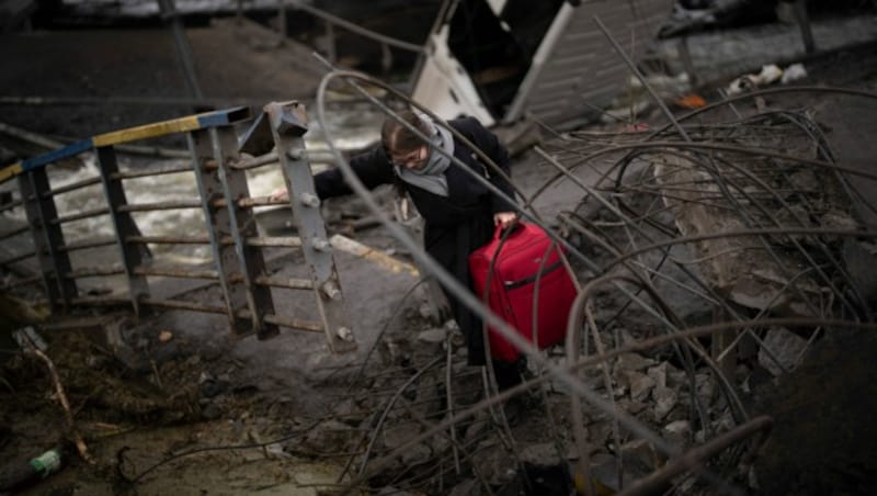 Eine Frau in Kiew rettet sich über eine zerstörte Brücke. (Bild: AP)