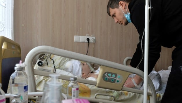 Ein Ukrainer kümmert sich um seinen verwundeten Siebenjährigen in einem Krankenhaus. (Bild: AFP )