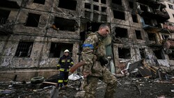 Ein ukrainischer Soldat und ein Feuerwehrmann vor einem zerbombten Gebäude in Kiew. (Bild: AP/Vadim Ghirda)