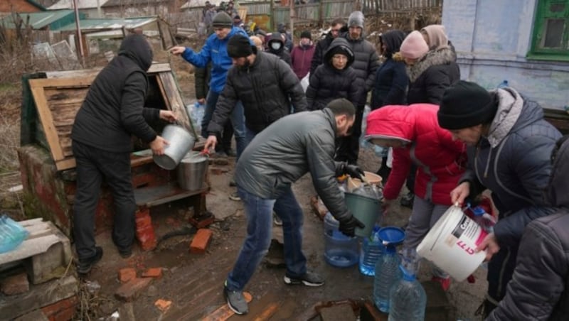 Menschen in Mariupol schöpfen Wasser aus einem Brunnen. (Bild: AP/Evgeniy Maloletka)