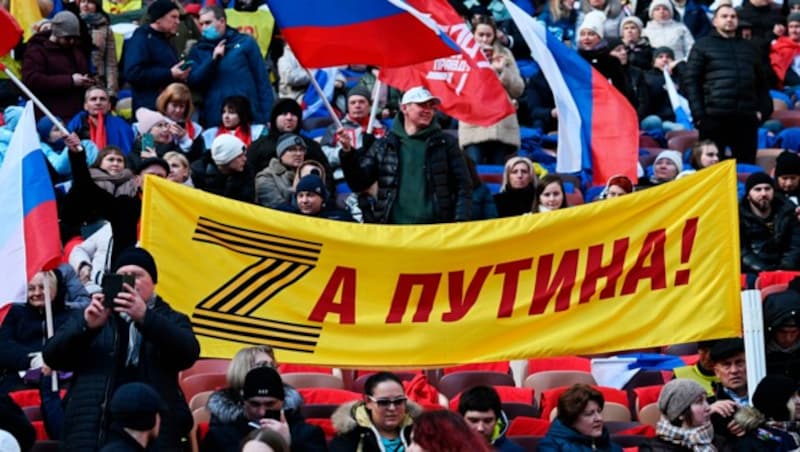 „Für Putin“ steht auf dem Transparent, das Russen bei der Jahrestagsfeier zur „Wiedervereinigung“ der Krim mit Russland im Moskauer Luzhniki-Stadion hochhalten. (Bild: AP/Pool Sputnik Host Photo Agency)