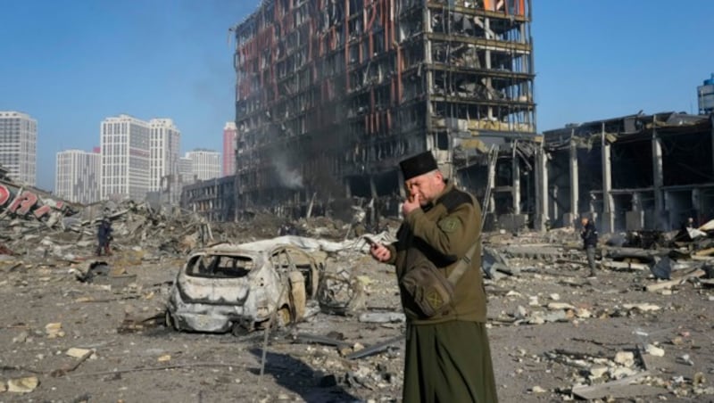 Ein ukrainischer Priester betet vor einem durch einen russischen Angriff völlig zerstörten Einkaufszentrum in Kiew. (Bild: AP)