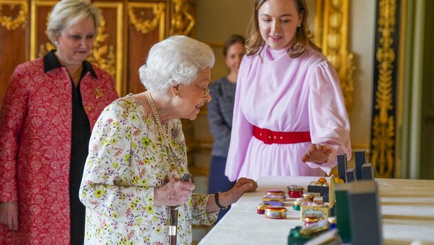 Die Königin lässt sich Produkte des Porzellan- und Emaille-Herstellers Halcyon Days zeigen. (Bild: APA/Photo by Steve Parsons/AFP)